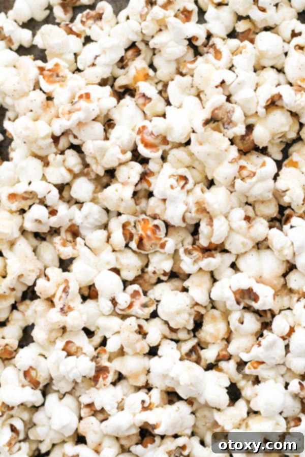 Cinnamon sugar popcorn spread in a single layer on a baking tray, ready for the oven.