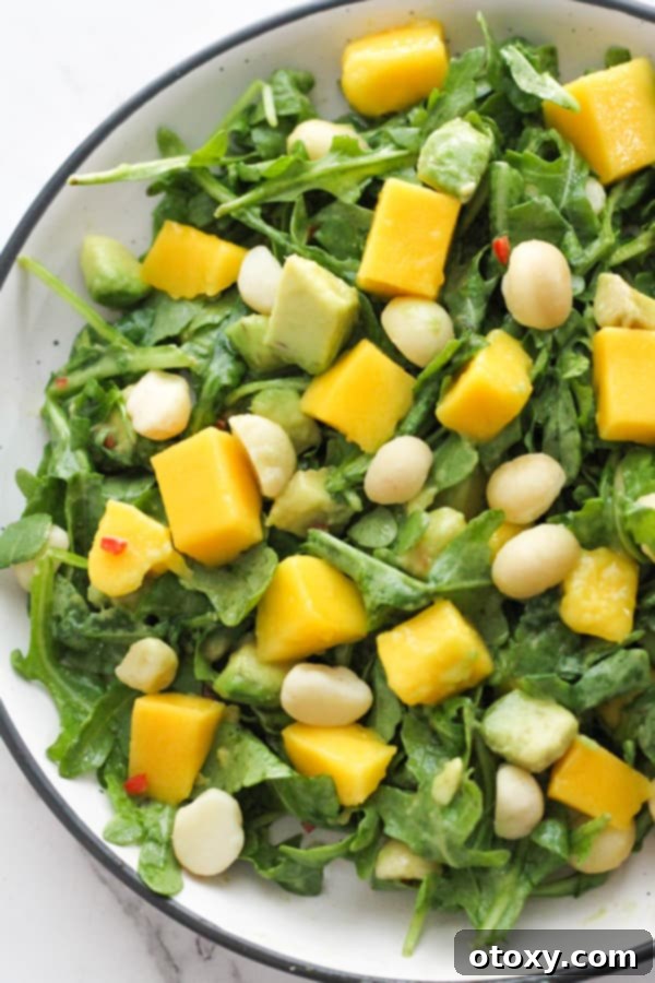 Fresh Mango Avocado Salad in a pristine white bowl, garnished with herbs and a hint of red chili.