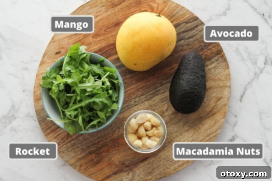Fresh salad ingredients including mango, avocado, macadamia nuts, and dressing components laid out on a rustic wooden board.