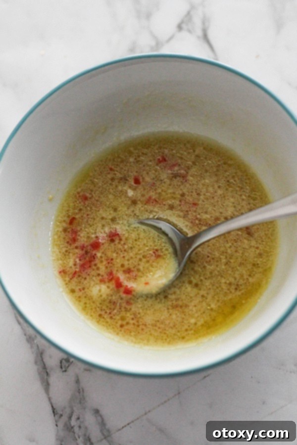 Freshly prepared salad dressing, a vibrant yellow vinaigrette, in a clear glass bowl, ready to be drizzled.