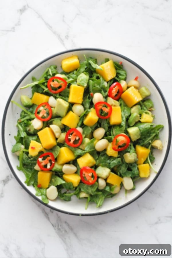 Beautifully arranged Mango Avocado Salad in a white bowl, garnished with thin slices of red chili for a touch of spice.