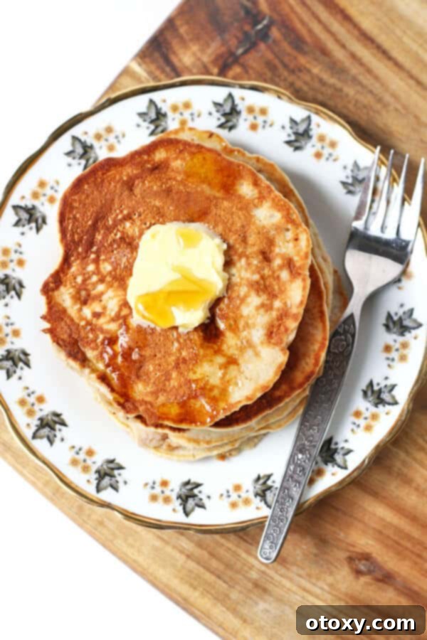 fluffy healthy banana pancakes stacked on a patterned plate with a square of butter and maple syrup drizzled on top