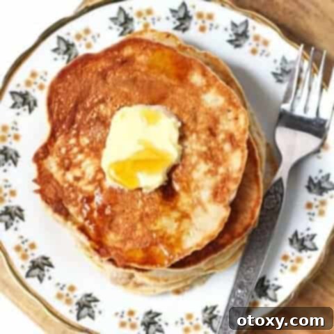healthy banana pancakes stacked on a pattered plate with butter and maple syrup on top