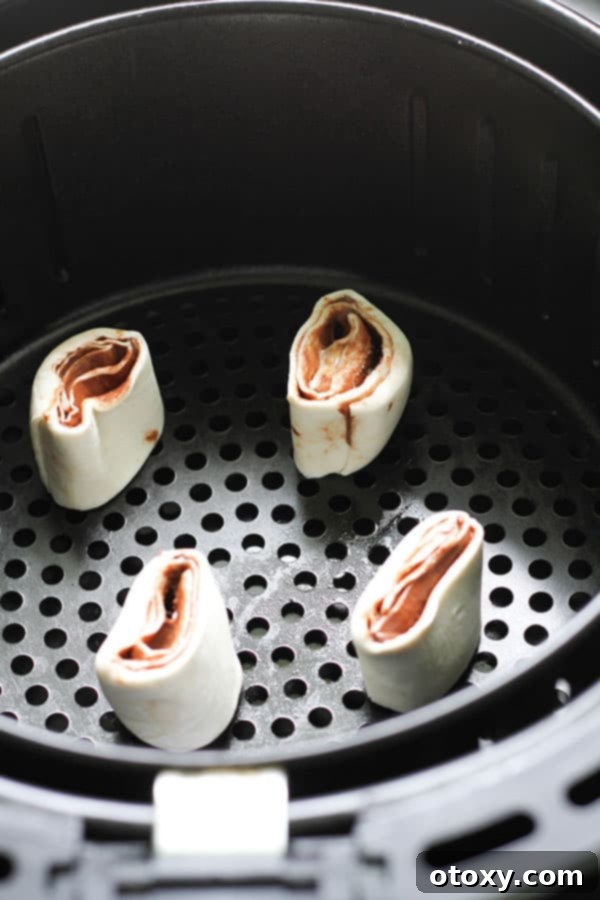 Chocolate Nutella Swirl Pastries Baked or Air Fried 9 uncooked pinwheels arranged neatly in an air fryer basket.
