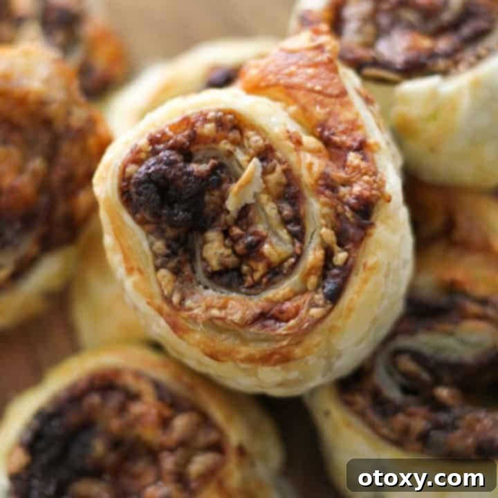 Easy Vegemite and Cheese Pinwheels Baked or Air Fried 11 Delicious Vegemite and cheese pinwheels, golden and flaky, stacked on a wooden board.