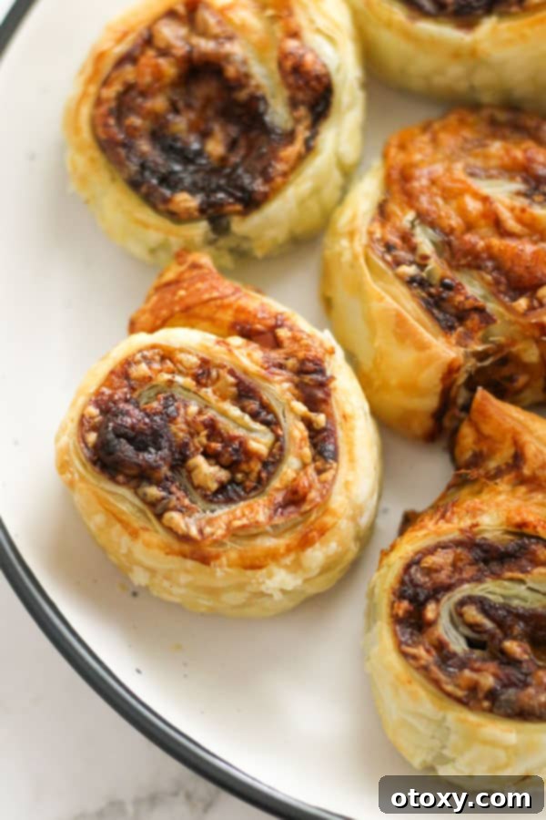 Easy Vegemite and Cheese Pinwheels Baked or Air Fried 3 Close-up of golden Vegemite and cheese pinwheels arranged neatly on a crisp white plate, ready to be served.