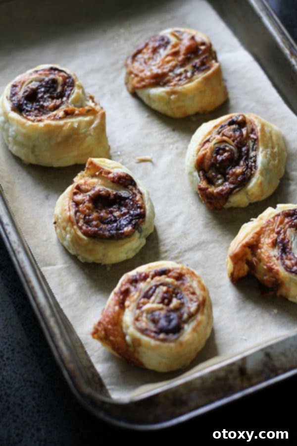 Easy Vegemite and Cheese Pinwheels Baked or Air Fried 8 Freshly baked Vegemite and cheese pinwheels on a baking tray, showcasing their golden-brown color and delicious appearance.