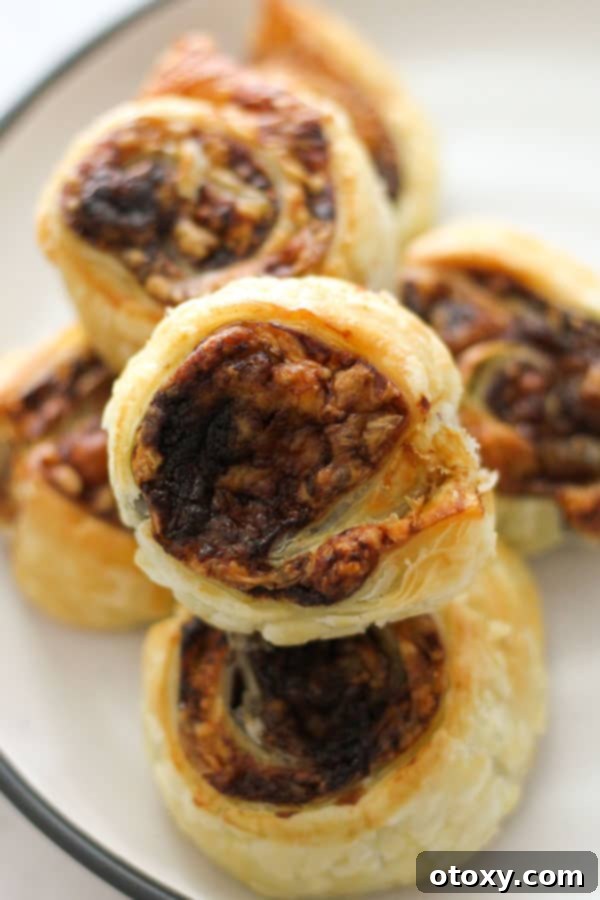 Easy Vegemite and Cheese Pinwheels Baked or Air Fried 10 A stack of perfectly golden and flaky Vegemite and cheese pinwheels on a pristine white plate, ready to be enjoyed.