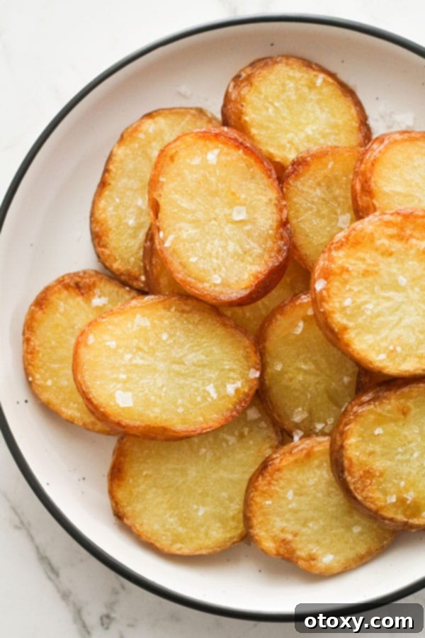 Crispy salt and vinegar potatoes perfectly roasted, served on a white plate ready to eat.