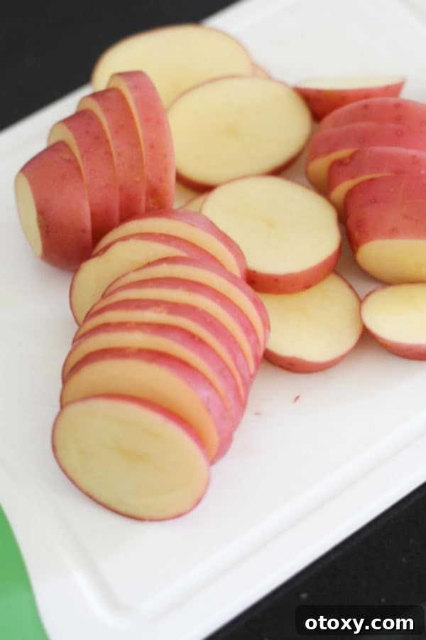 A potato being expertly sliced into even rounds on a chopping board.