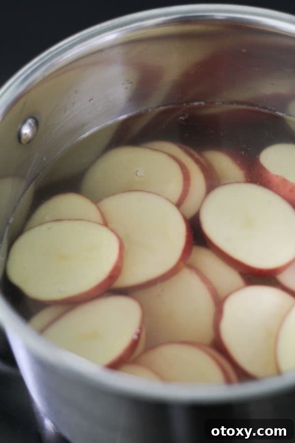 Potato rounds simmering in a saucepan with vinegar and water, infusing with flavor.