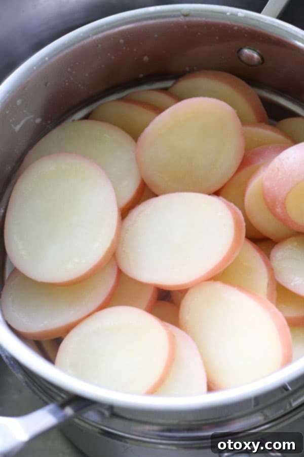A close-up shot of boiled potato rounds draining in a colander, ready for roasting.