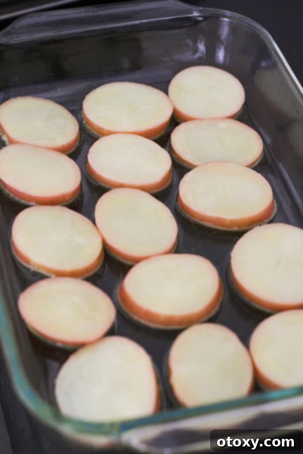A close-up of a large roasting dish with a thin layer of olive oil heating in the oven.