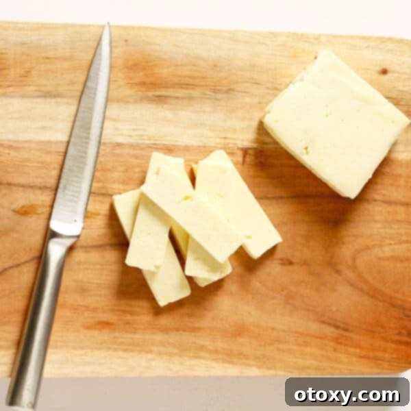 Sliced halloumi cheese, golden and crispy, ready to be added to a salad, on a rustic wooden cutting board