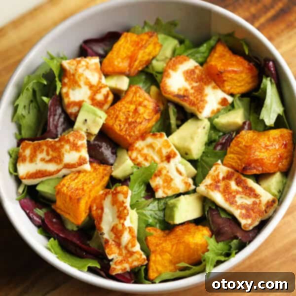 Close-up shot of a vibrant pumpkin, halloumi, and avocado salad, artfully arranged in a rustic bowl, showcasing its appetizing colors and textures