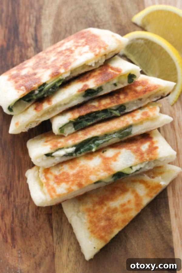 Sliced Spinach and Feta Gozleme pieces neatly arranged on a rustic wooden board, showcasing the vibrant green spinach and melted cheese filling.