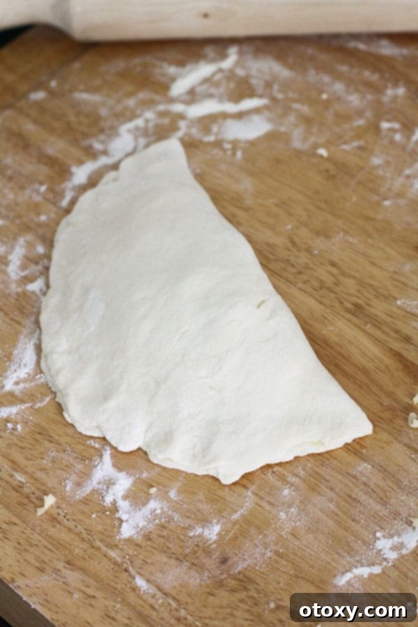 A semi-circle of two-ingredient dough, neatly folded over its spinach and feta filling, with the edges crimped tightly with a fork.