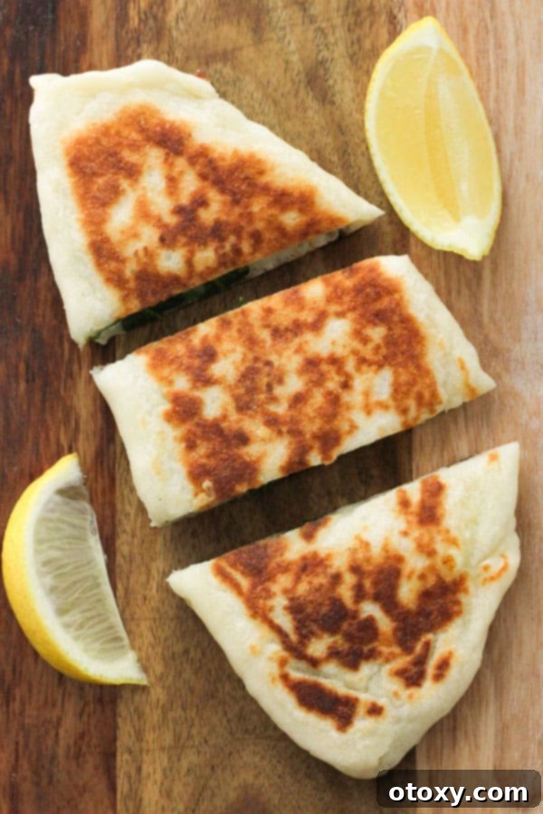 Whole, golden-brown Spinach and Feta Gozleme resting on a wooden board, perfectly cooked and ready to be sliced.