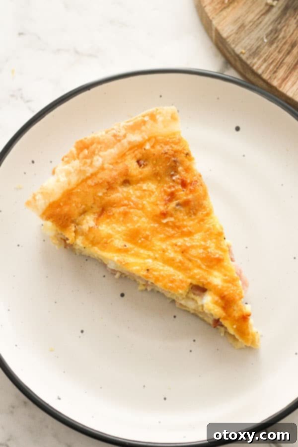 A single, generous slice of bacon and egg pie presented on a pristine white plate, highlighting the delicious layers.