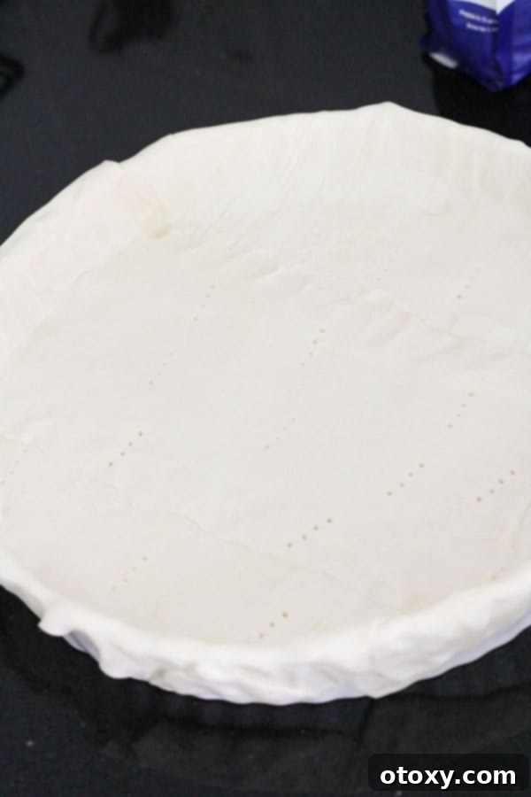 A puff pastry sheet perfectly lining a round quiche dish, ready for filling.