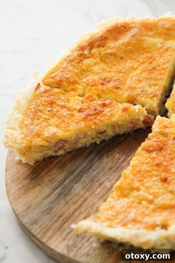 A mouth-watering image of a bacon and egg pie, with a slice already removed, showing the remaining delicious portion on a wooden board.