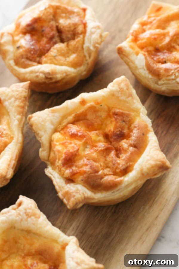 An array of freshly baked mini quiches, still in a muffin tray, on a rustic wooden board.