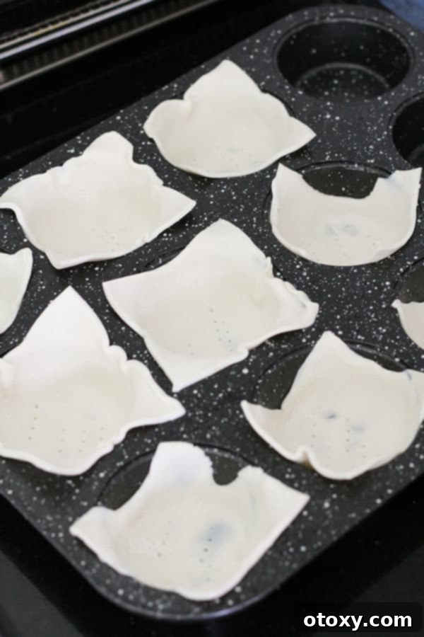 Puff pastry squares perfectly pressed into a muffin tray, ready for filling.