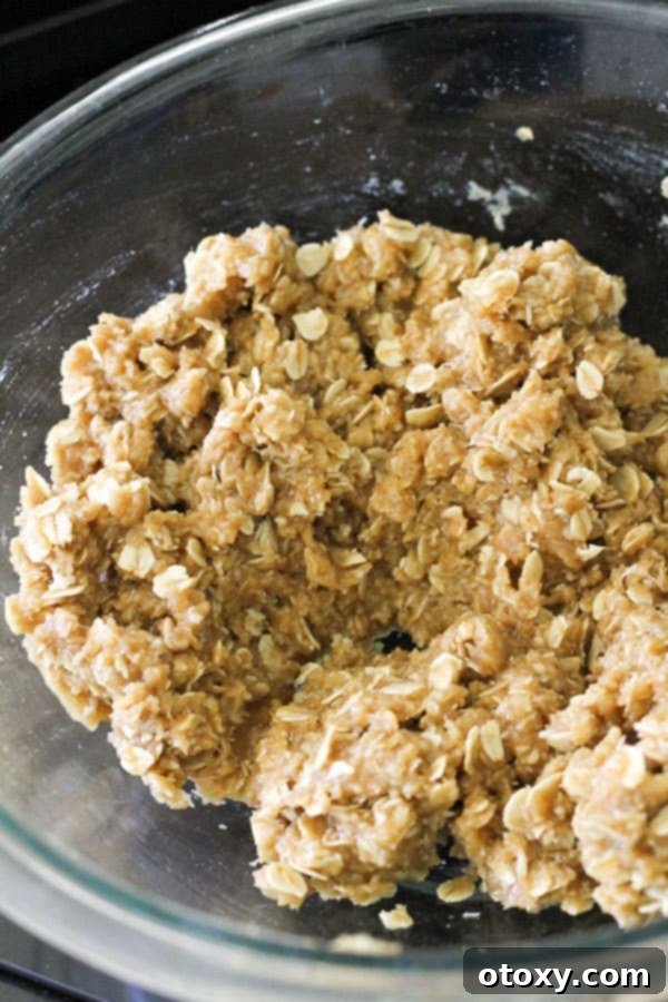 Anzac biscuit mixture, ready to be shaped, in a glass mixing bowl.