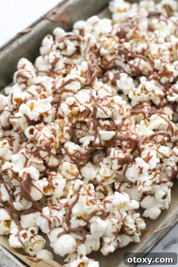 Decadent Chocolate Popcorn 9 popcorn drizzled with chocolate on a baking tray.