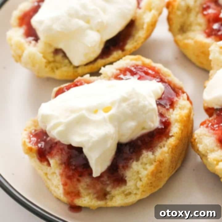 Golden Air Fryer Scones 11 A beautifully presented air fryer scone topped with jam and cream on a white plate, highlighting its golden crust and fluffy texture.