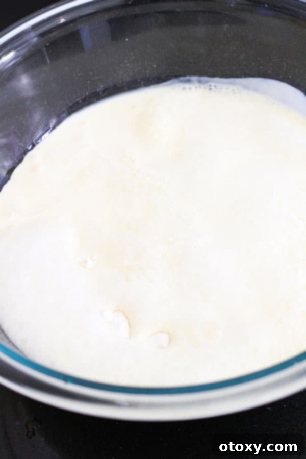 Golden Air Fryer Scones 5 A clear glass bowl containing the sifted flour, sugar, cream, and lemonade, perfectly mixed to form a soft, sticky scone dough.