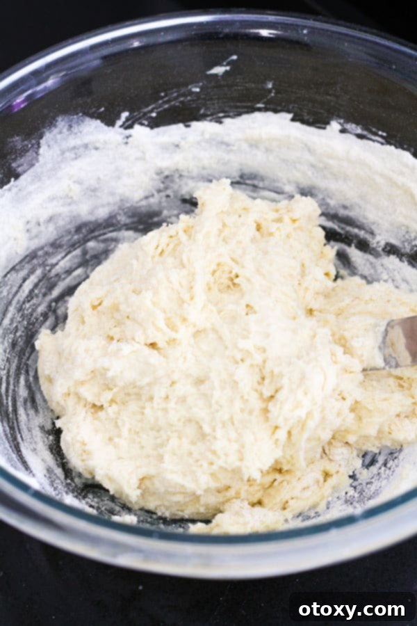 Golden Air Fryer Scones 6 The scone dough, now fully combined and sticky, resting in a large glass bowl, ready for the next step of shaping and cutting.