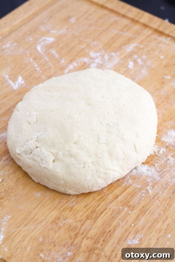 Golden Air Fryer Scones 7 The scone dough expertly shaped into a large, thick disc on a wooden board, showcasing its readiness for cutting into individual rounds.