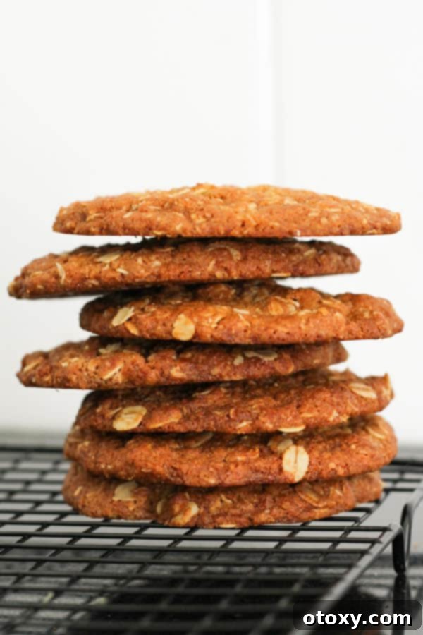 A neat stack of crunchy Anzac biscuits cooling on a wire rack, showcasing their golden-brown color and inviting texture.