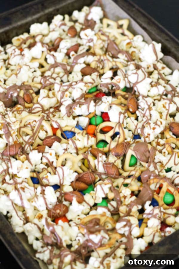 Popcorn and other mix components on a baking tray, artfully drizzled with melted chocolate.