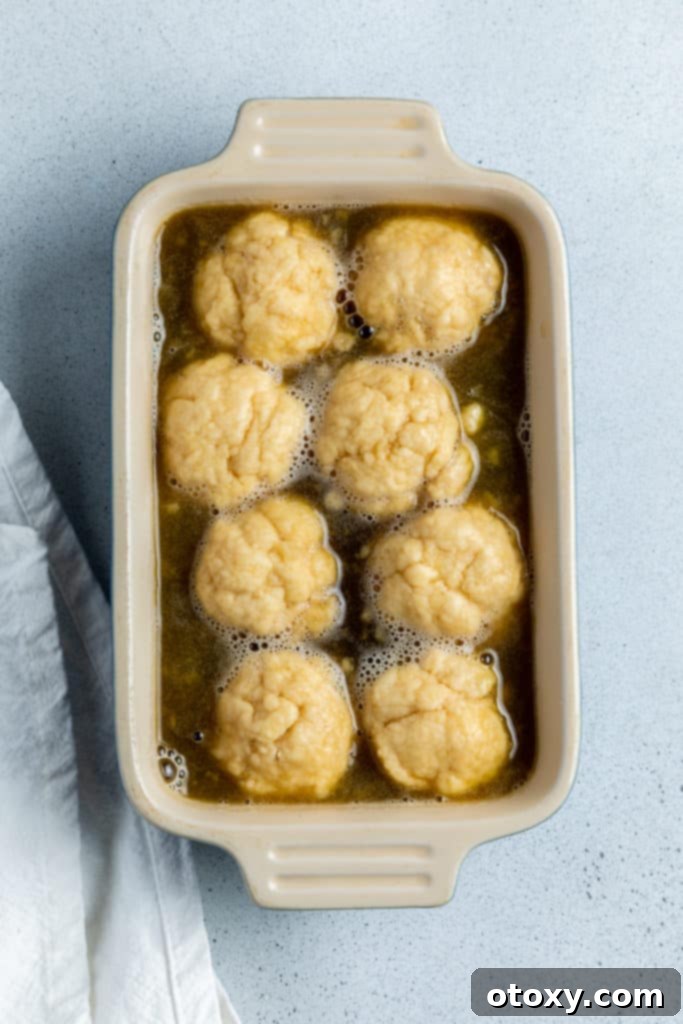 balls of dough covered in a syrup sauce in a baking dish.