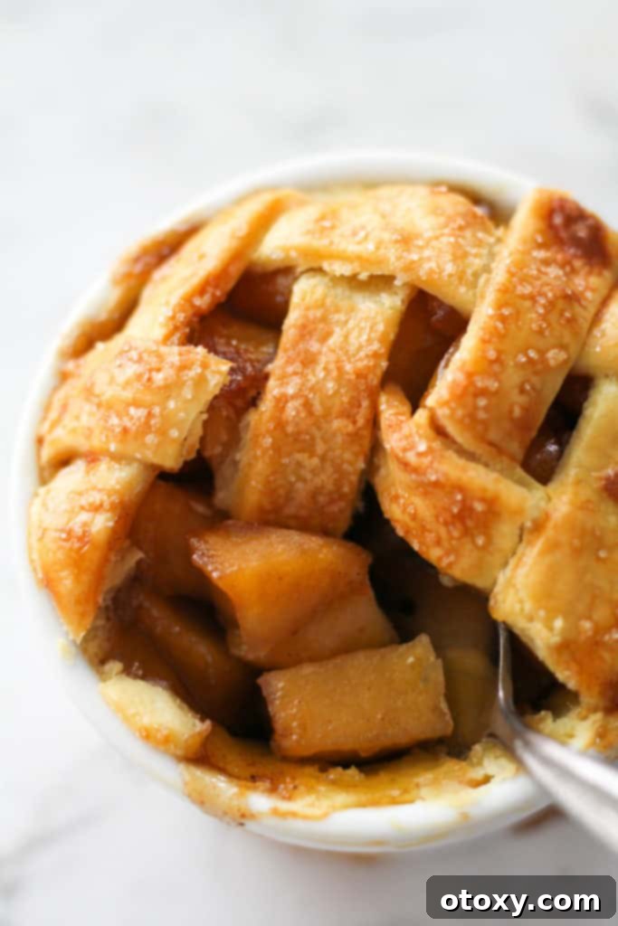 a fork scooping apple pieces from a mini apple pie.