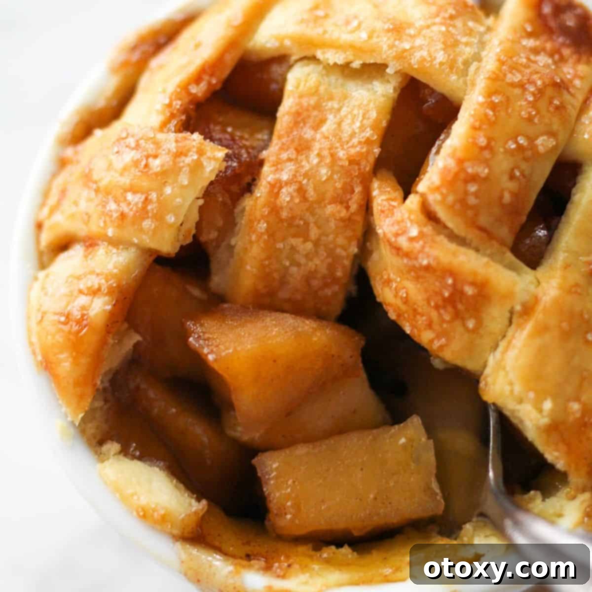 a fork scooping apple pieces from a mini apple pie.