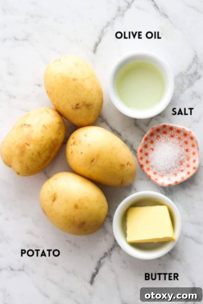 A flat lay of ingredients for air fryer smashed potatoes, including baby potatoes, olive oil, butter, and sea salt.