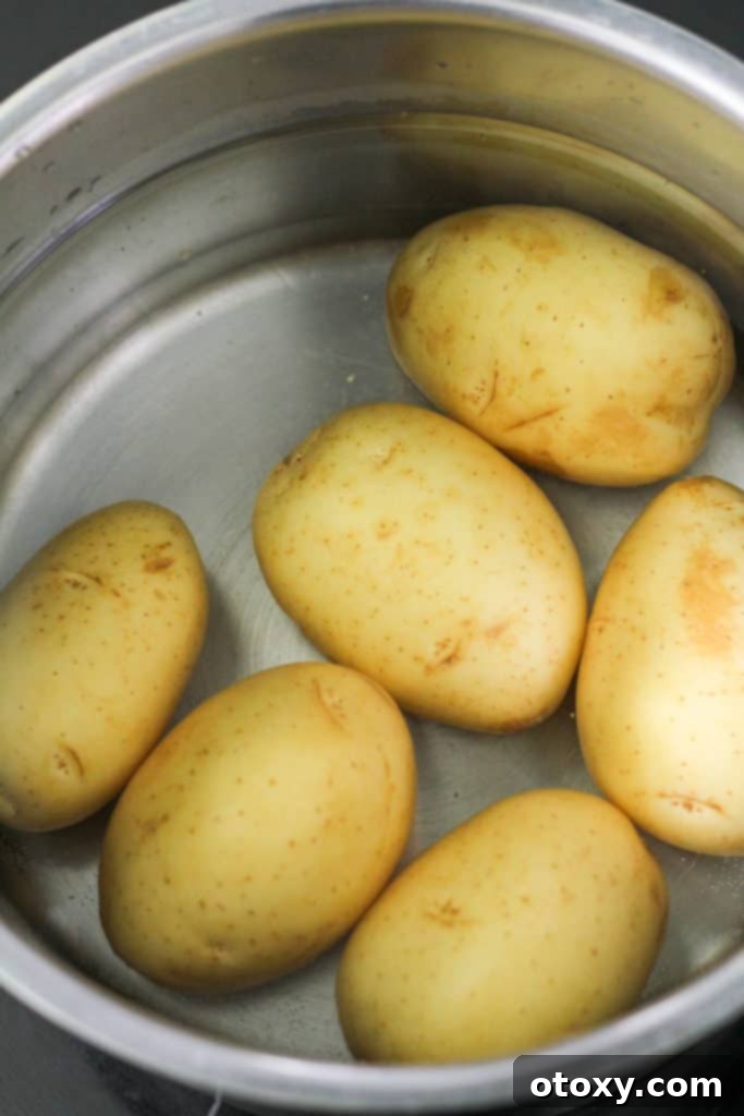 Small white potatoes submerged in water in a saucepan, ready for boiling.