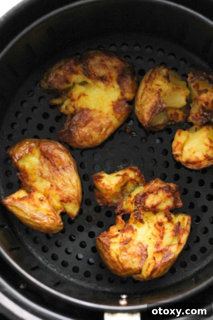 Air fryer basket filled with perfectly golden and crispy smashed potatoes.