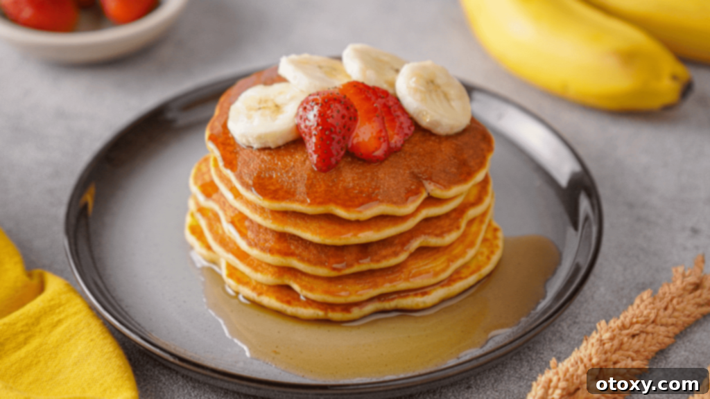 Ultimate 40g Protein Pancakes 12 Protein Pancake with banana, strawberries and maple syrup toppings on the plate