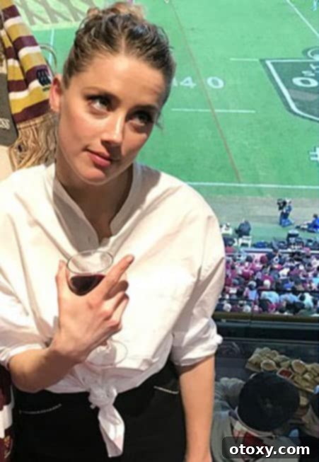 A candid photo taken by Amber Heard at a football game, showing a crowd in the background where a couple (the author and her partner) can be spotted in the bottom right corner.