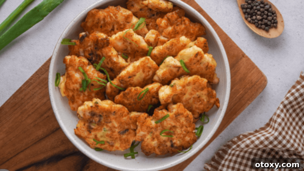 Crispy Chicken Delights 2 Crispy golden-brown chicken fritters served on a pristine white plate, garnished with fresh herbs.