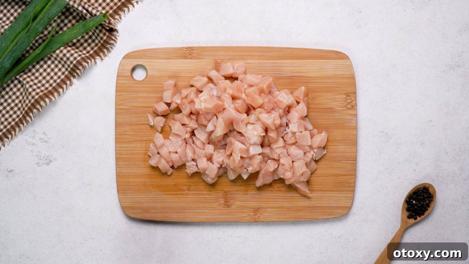 Crispy Chicken Delights 19 Finely diced raw chicken breast pieces neatly arranged on a wooden cutting board.