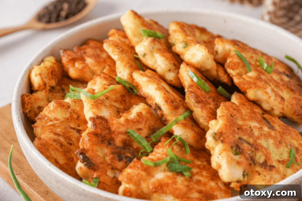 Crispy Chicken Delights 3 Close-up of golden brown chicken fritters stacked on a plate, showing their crispy texture and cheesy interior.