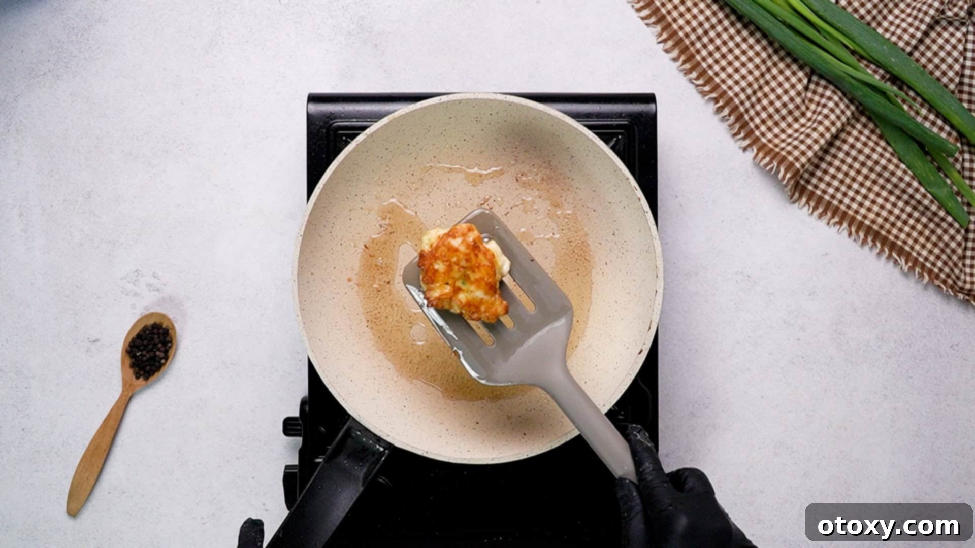 Crispy Chicken Delights 25 A kitchen spatula holding a perfectly golden-brown and crispy chicken fritter, fresh from the pan.