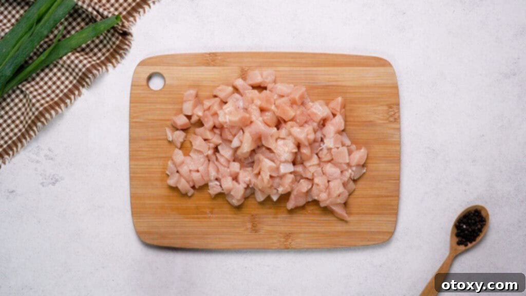 Crispy Chicken Delights 5 Finely diced raw chicken breast pieces neatly arranged on a wooden cutting board.