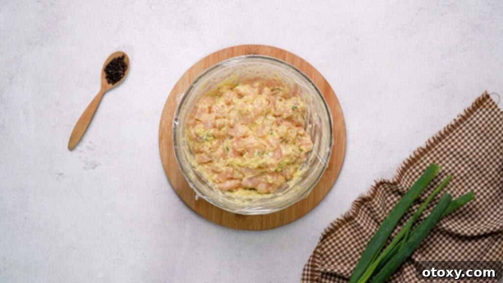 Crispy Chicken Delights 8 Mixing bowl containing the chicken fritter mixture, covered tightly with plastic wrap and ready for refrigeration.