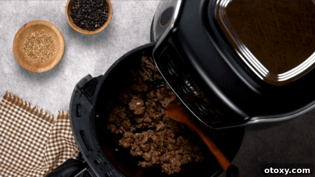 Air Fried Ground Beef Made Simple 11 Breaking up ground beef in the air fryer basket with a wooden spoon